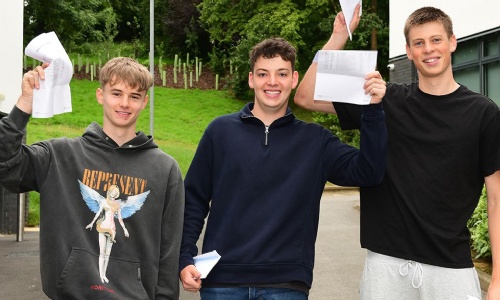 Three students smiling and holding up their A level results